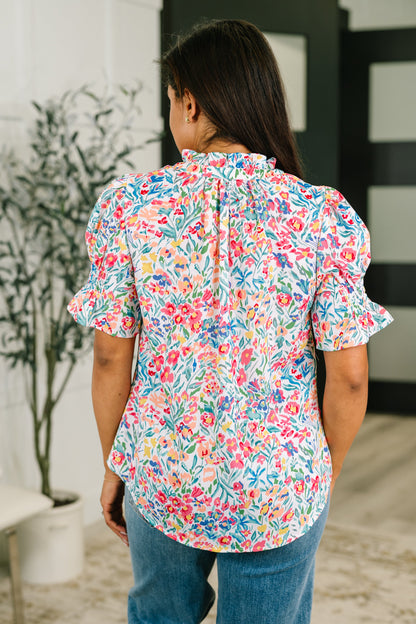 Woman wearing a colorful floral blouse in an indoor setting
