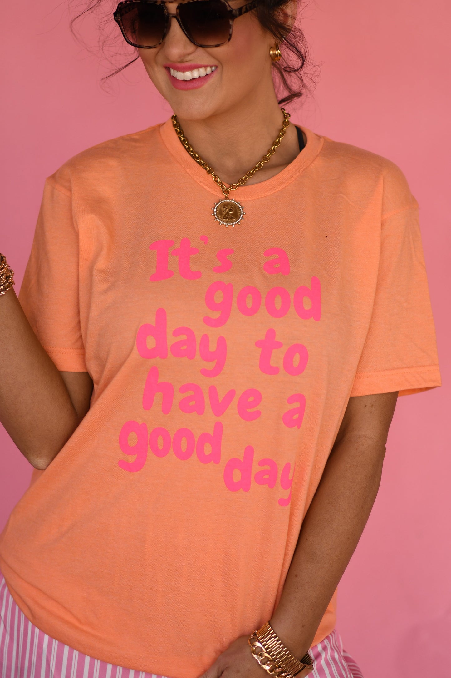Person wearing an orange t-shirt with pink text on a pink background