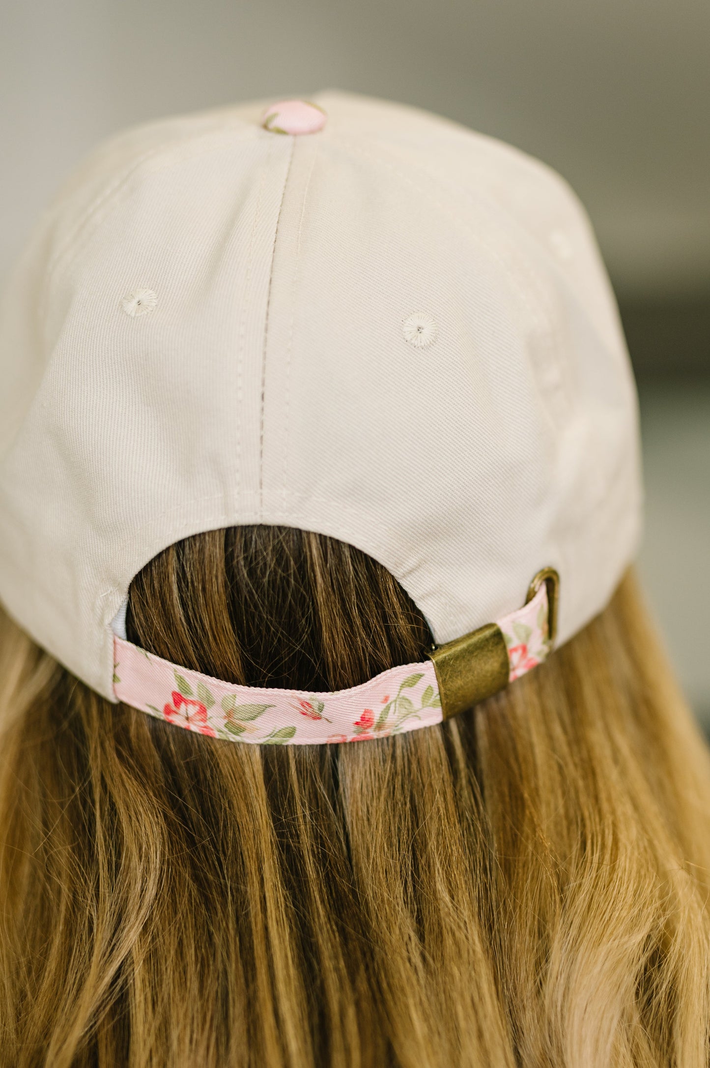 Beige cap with floral strap worn by a person with long hair