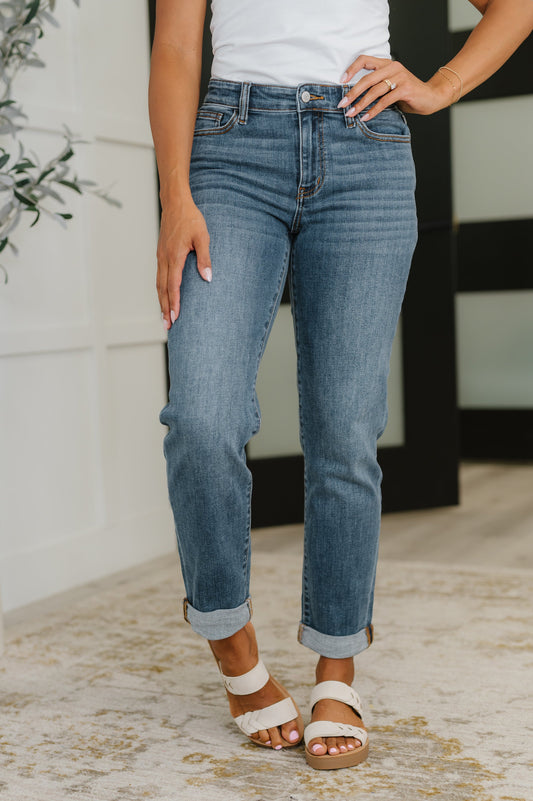Person wearing mid rise cuffed boyfriend blue jeans and white sandals indoors