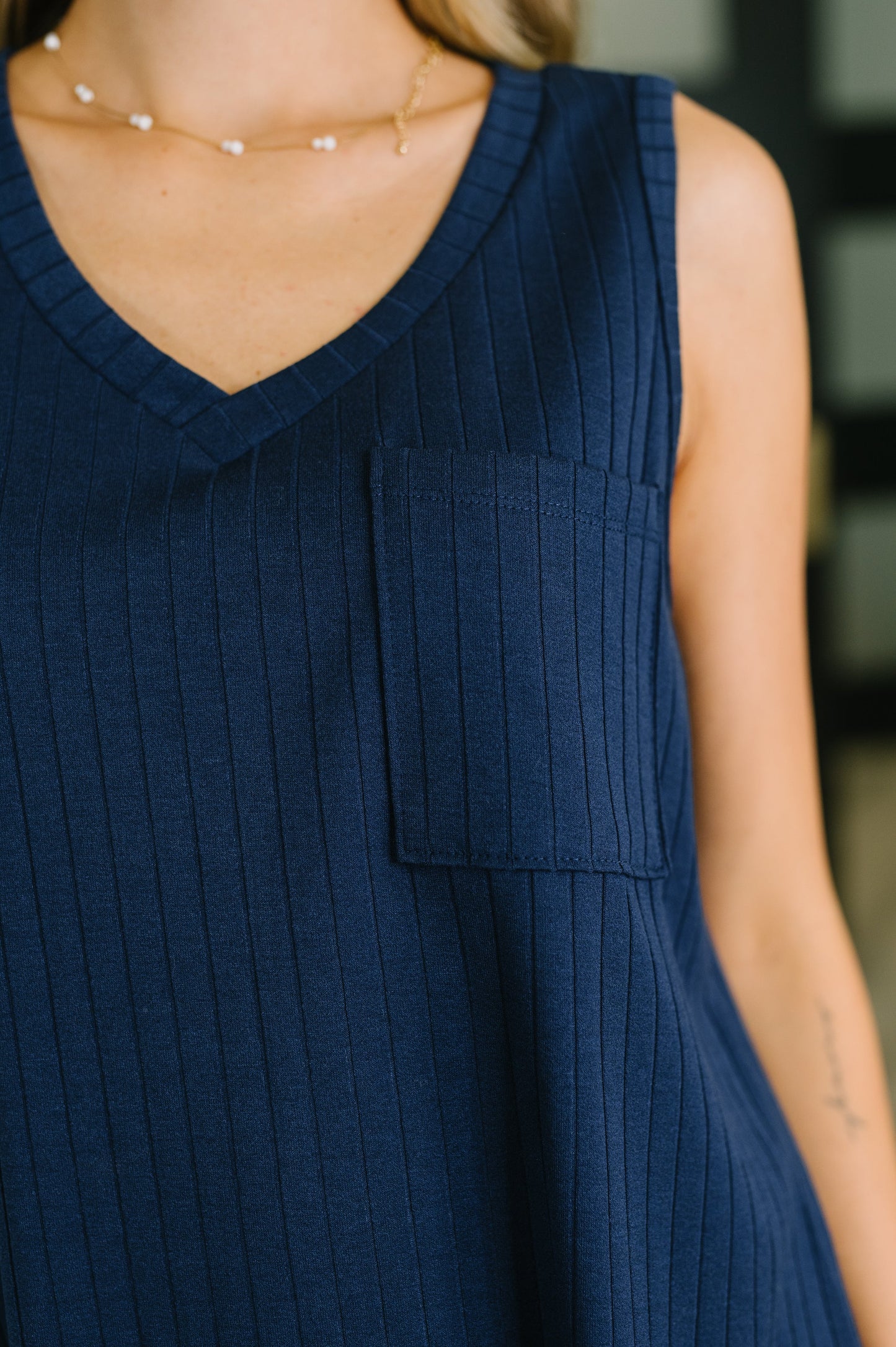 Navy blue sleeveless dress with a pocket on a blurred background