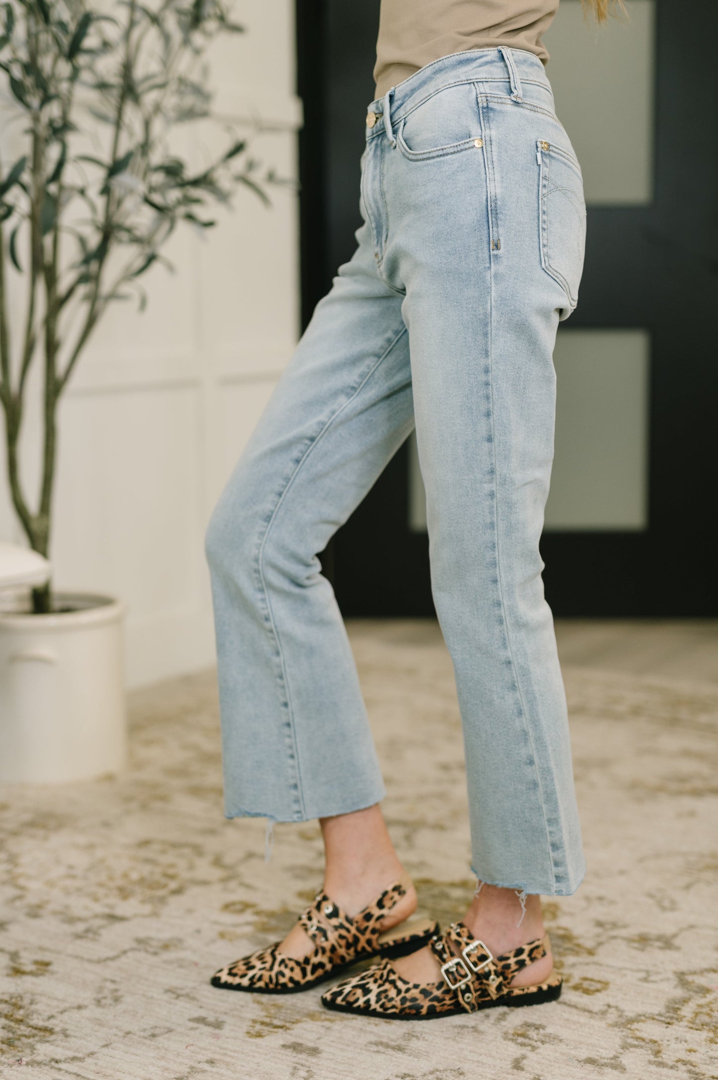 Person wearing light blue jeans and leopard print sandals in an indoor setting.