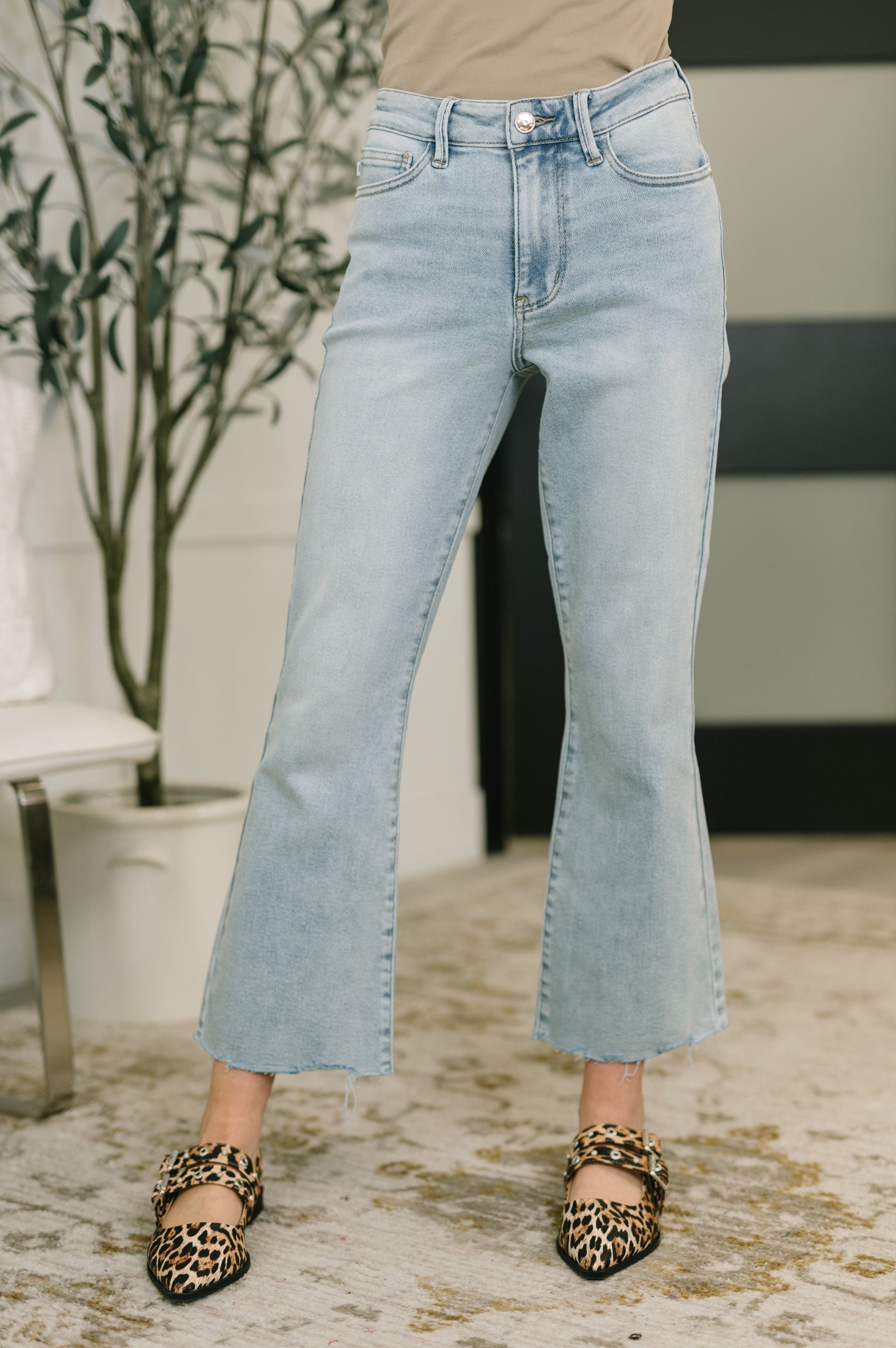 Person wearing light blue jeans with a blurred indoor background