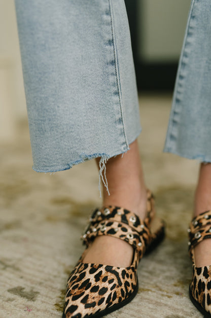 Leopard print shoes worn with light blue jeans on a textured surface