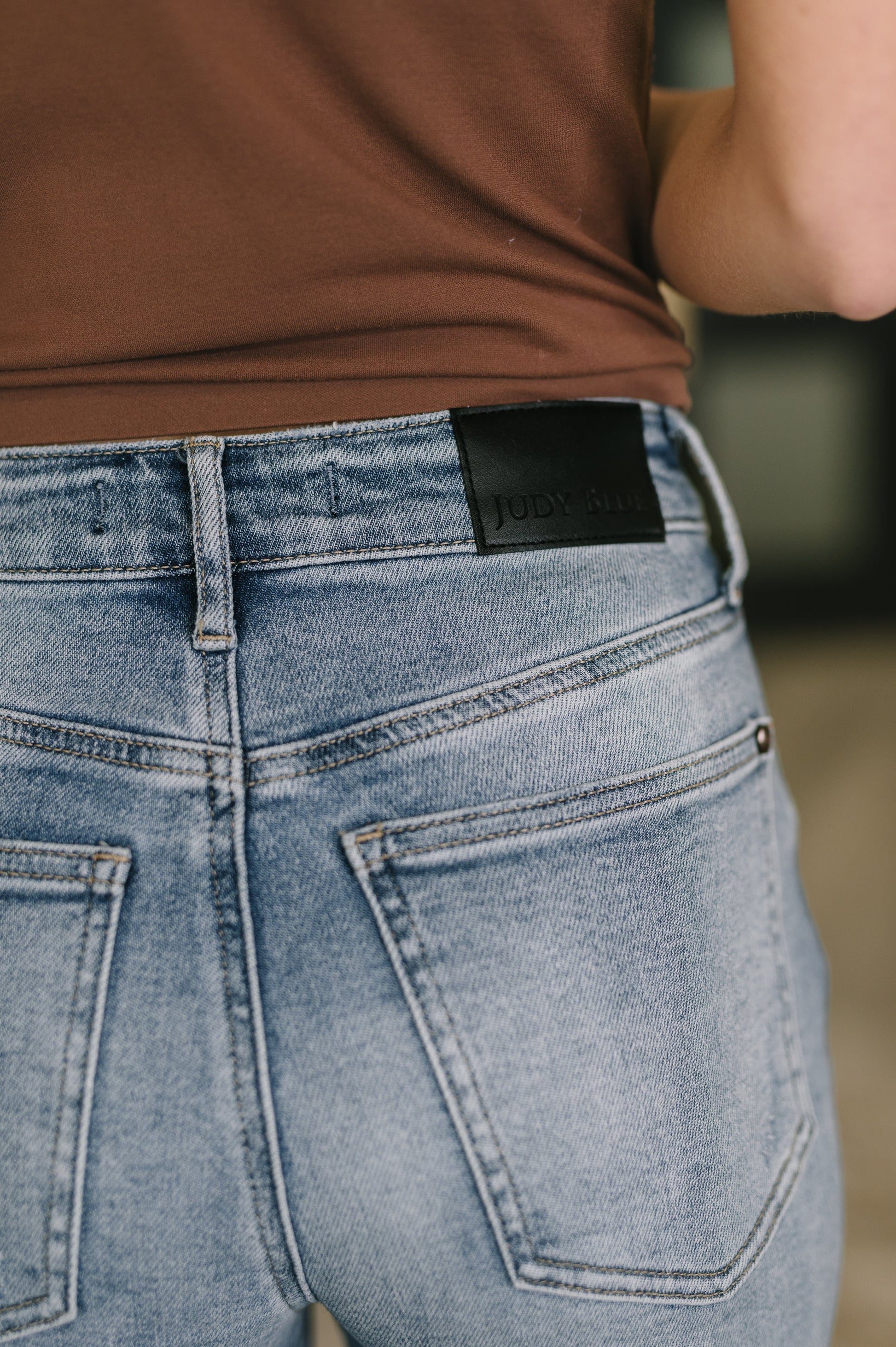 Close-up of blue jeans with a brand label on the back pocket, worn by a person.