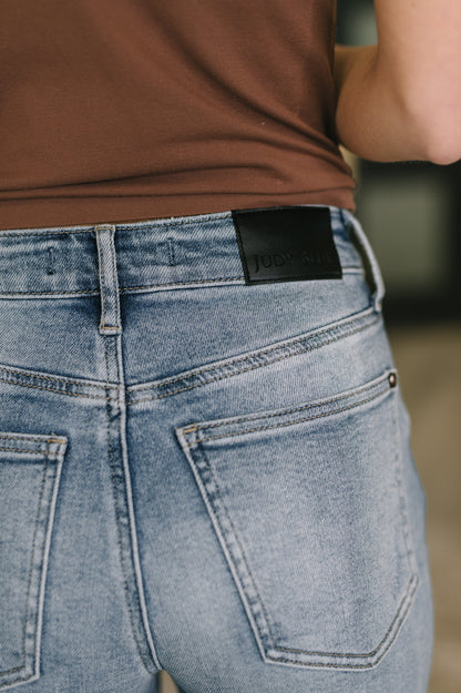 Close-up of blue jeans with a brand label on the back pocket, worn by a person.
