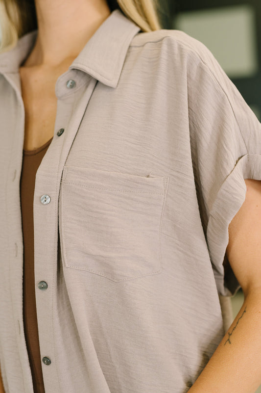 Close-up of a person wearing a beige button-up shirt with a blurred background