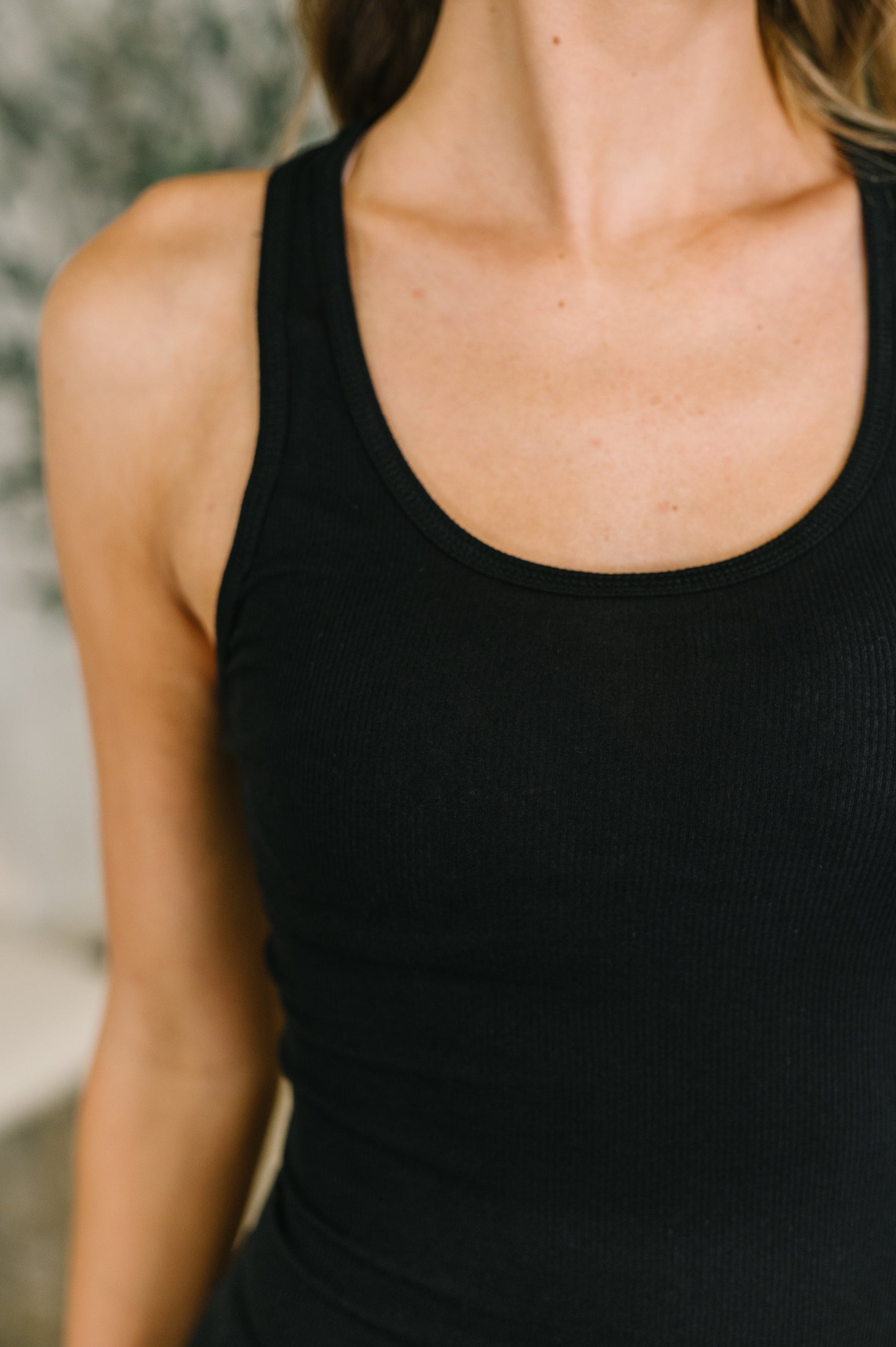 Close-up of a person wearing a black tank top with a blurred background