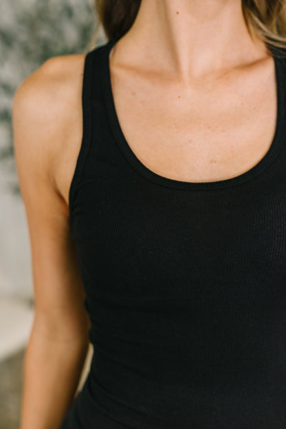 Close-up of a person wearing a black tank top with a blurred background