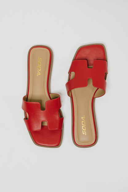 A pair of red leather slide sandals with an H-shaped strap, shown from top and side angles on a light gray background. The brand name 'VODAS' is printed in gold on the beige insoles.