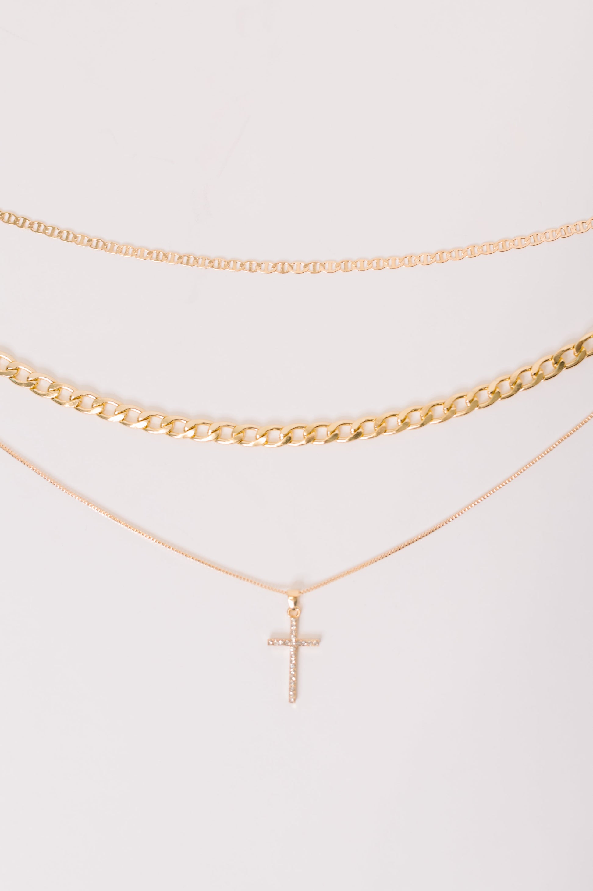 Gold necklace with a cross pendant on a white background