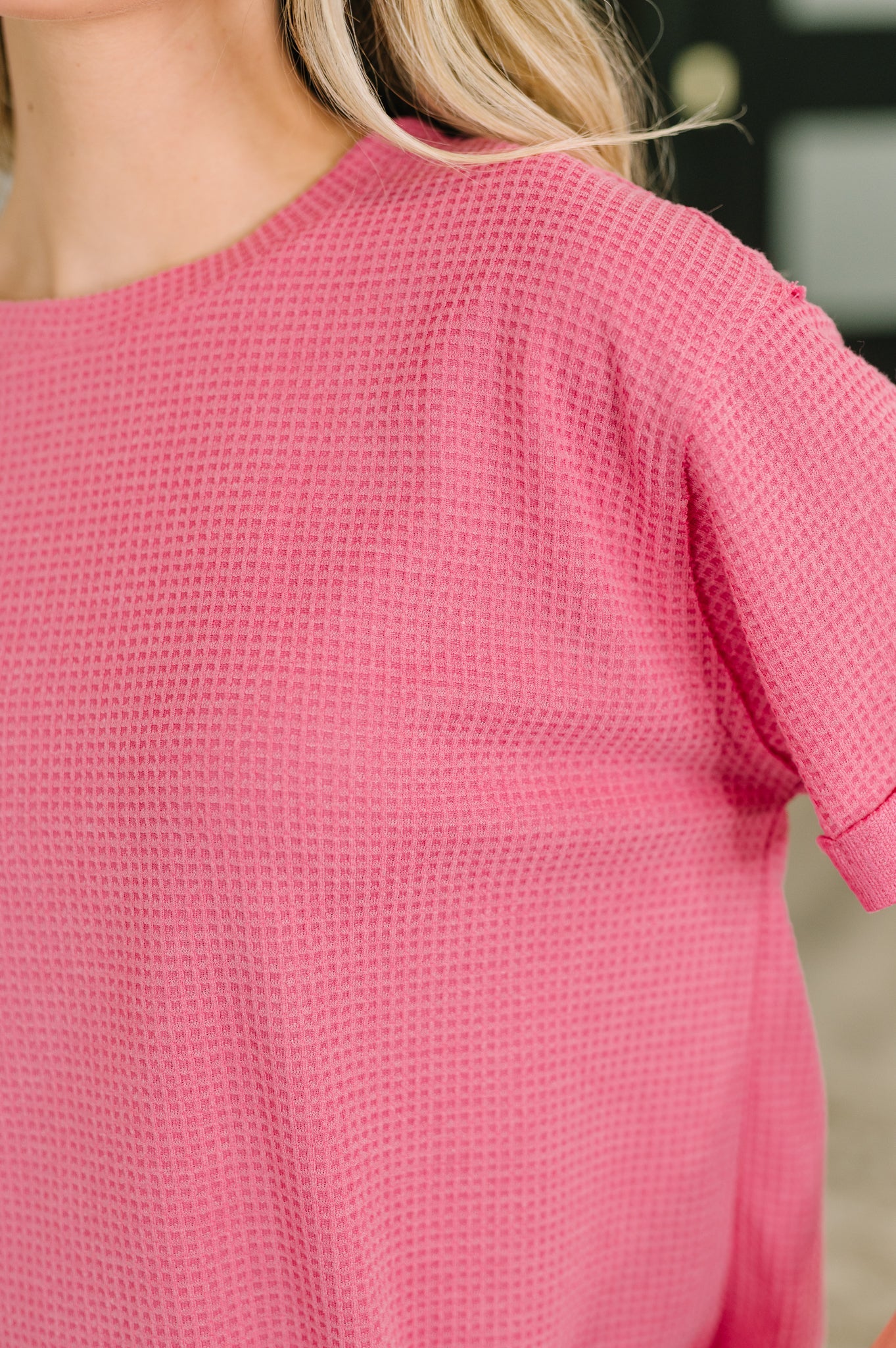 Close-up of a pink textured top worn by a person with blurred background
