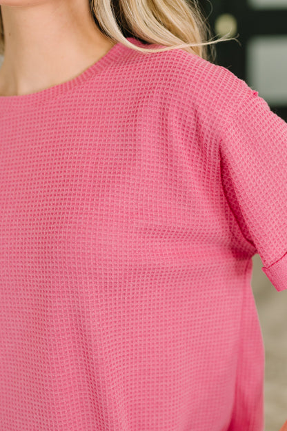 Close-up of a pink textured top worn by a person with blurred background
