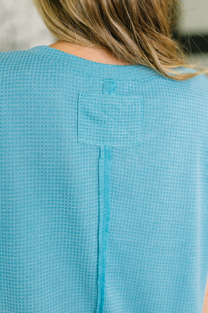 Close-up of a textured blue garment with a button detail.
