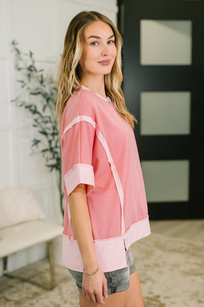 Woman wearing a pink top with white trim in an indoor setting
