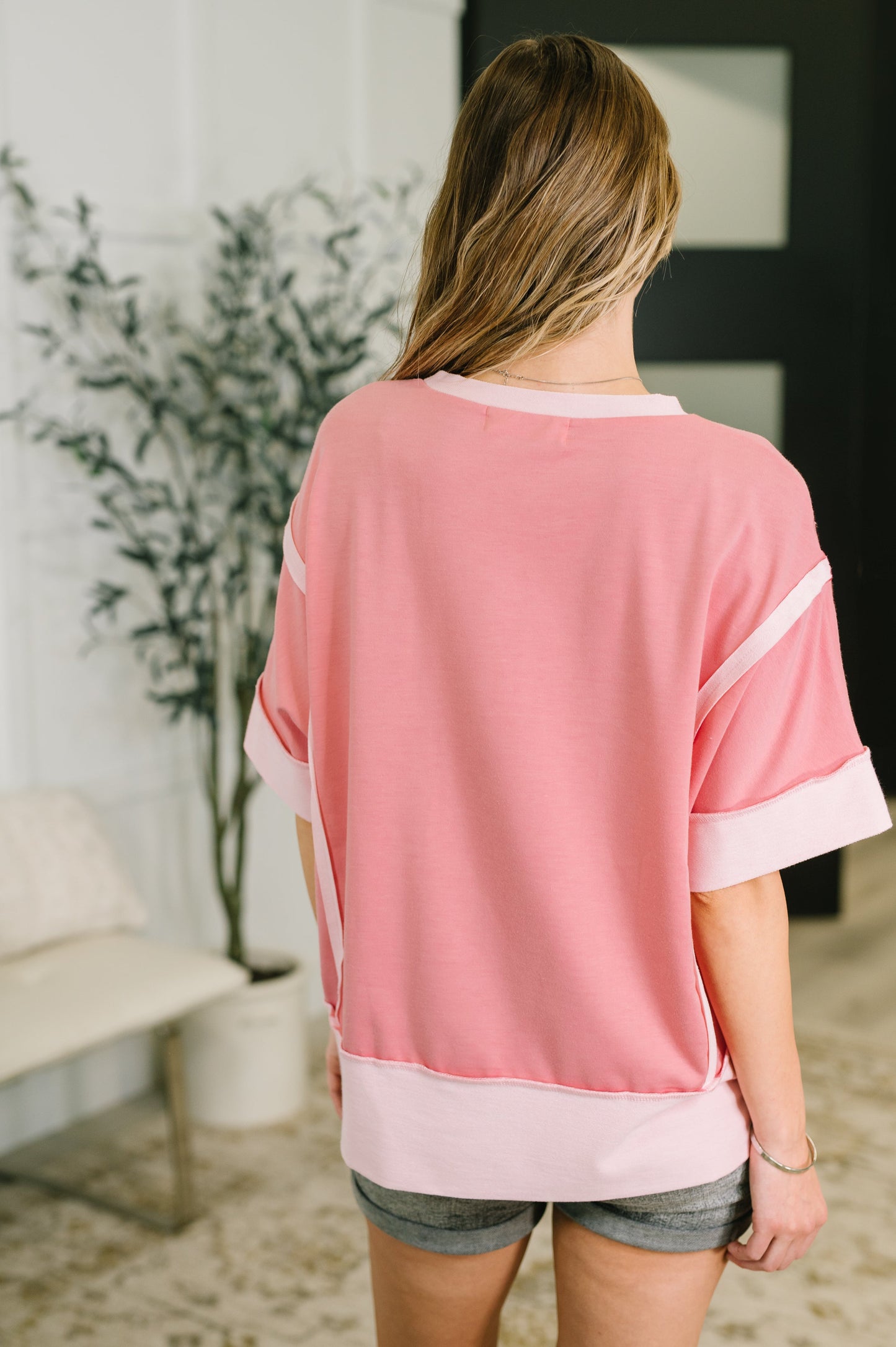 Woman wearing a pink and white top in an indoor setting