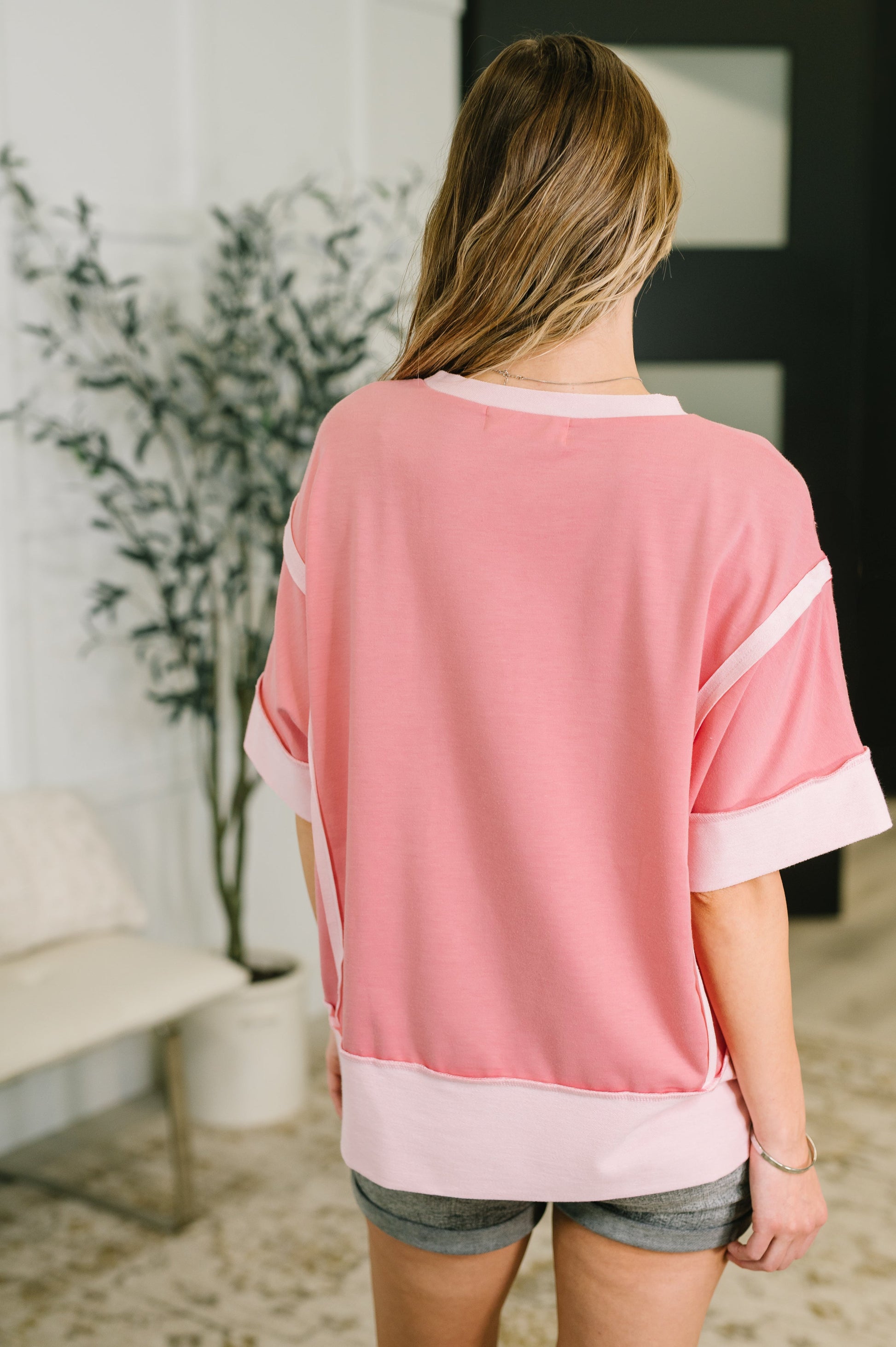 Woman wearing a pink and white top in an indoor setting