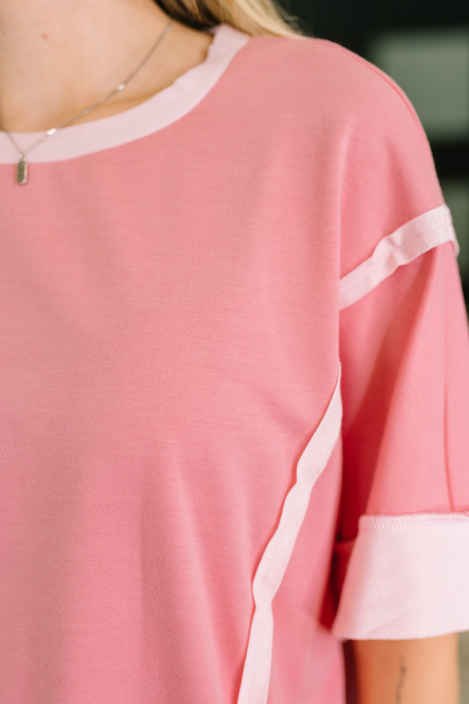 Close-up of a pink top with white trim on a blurred background