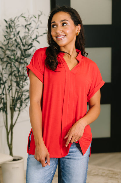 Woman wearing a red blouse and blue jeans indoors