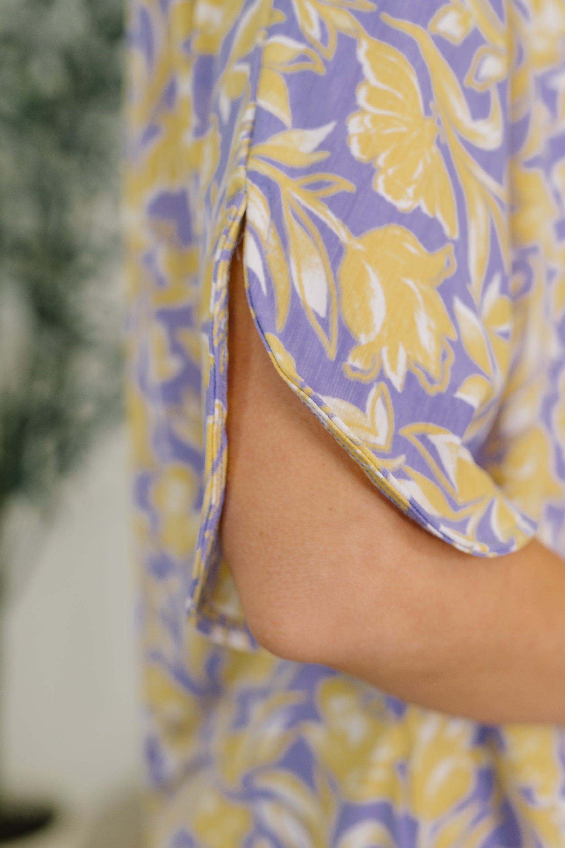 Close-up of a person wearing a purple and yellow floral dress.