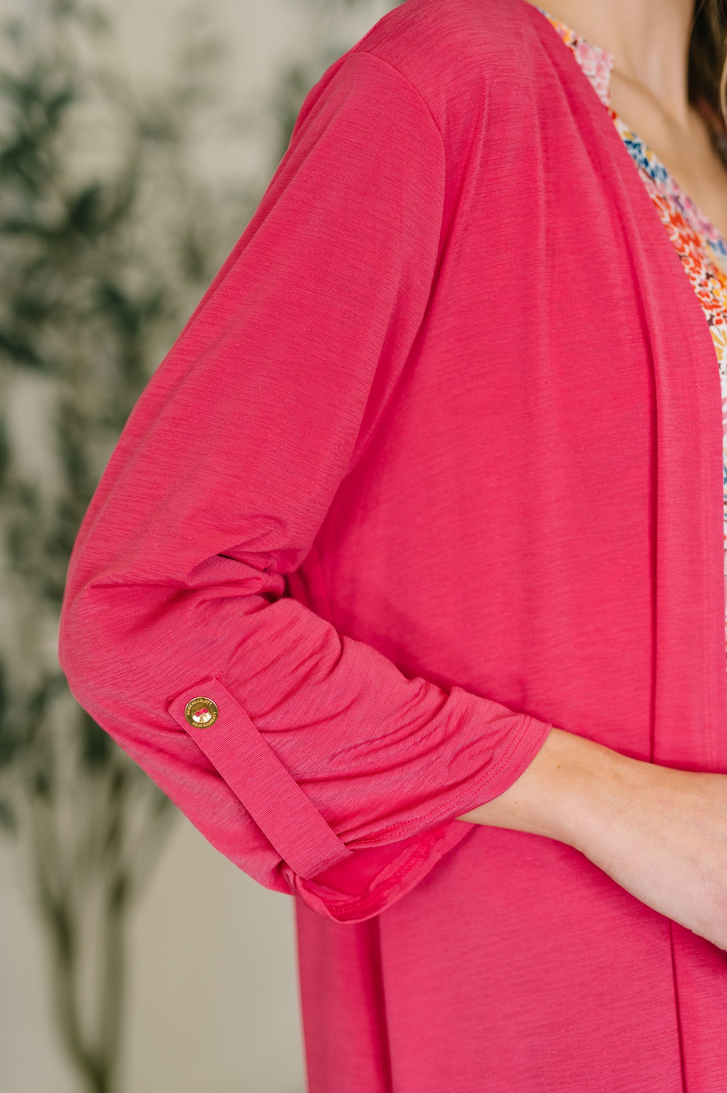 Close-up of a person wearing a bright pink cardigan with a blurred background