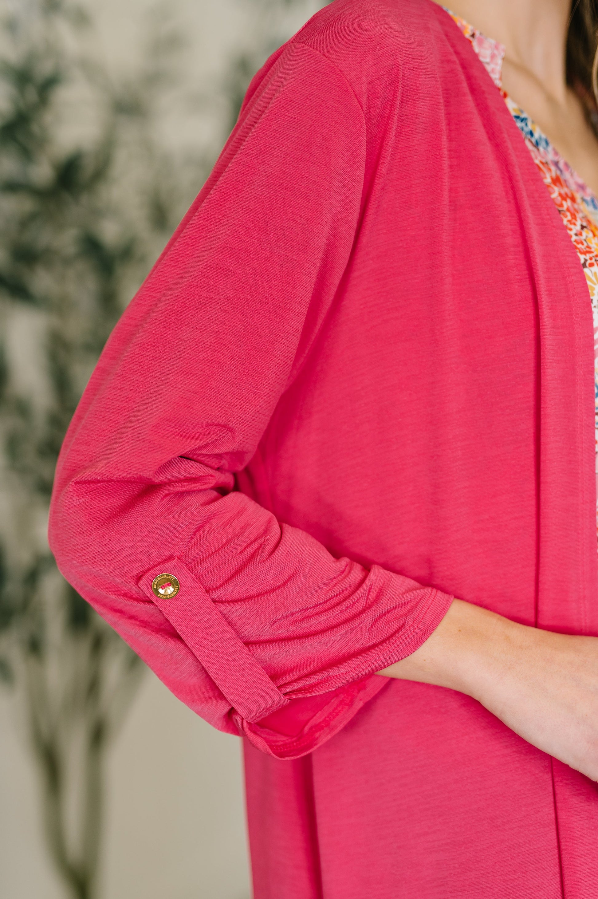 Close-up of a person wearing a bright pink cardigan with a blurred background
