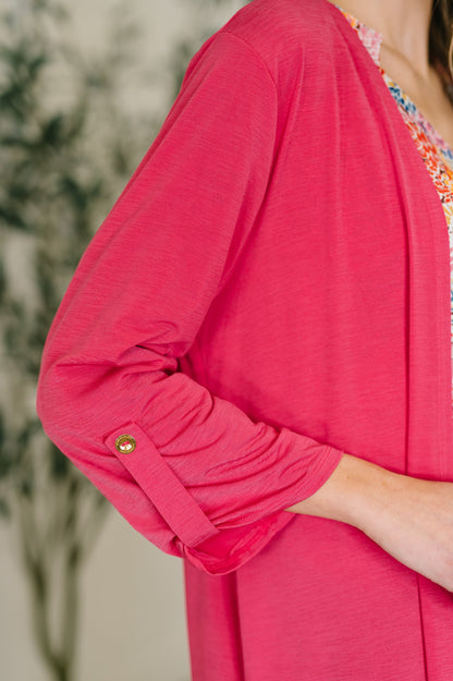 Close-up of a person wearing a bright pink cardigan with a blurred background