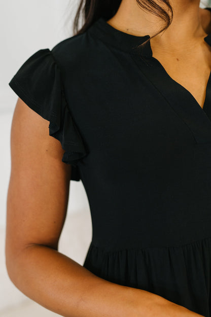 Black dress with ruffled sleeves on a neutral background