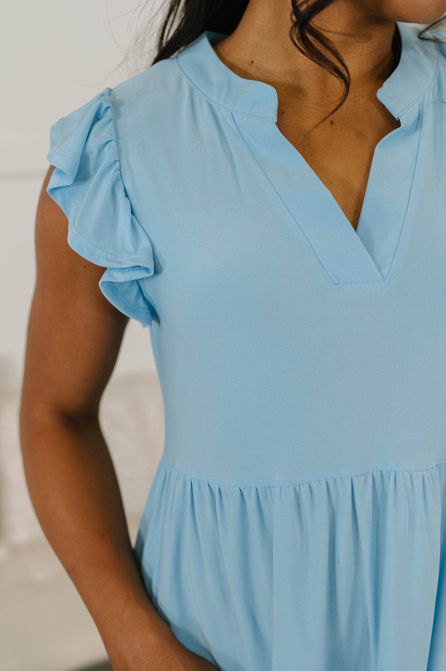 Light blue dress with ruffled sleeves worn by a person against a neutral background