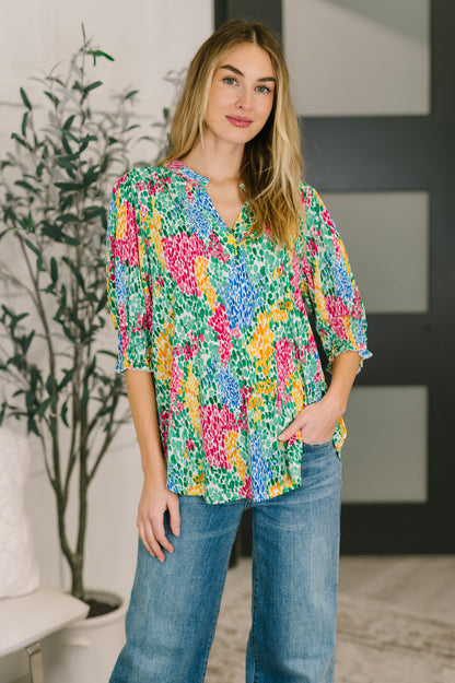 Woman wearing a colorful floral blouse and blue jeans indoors.