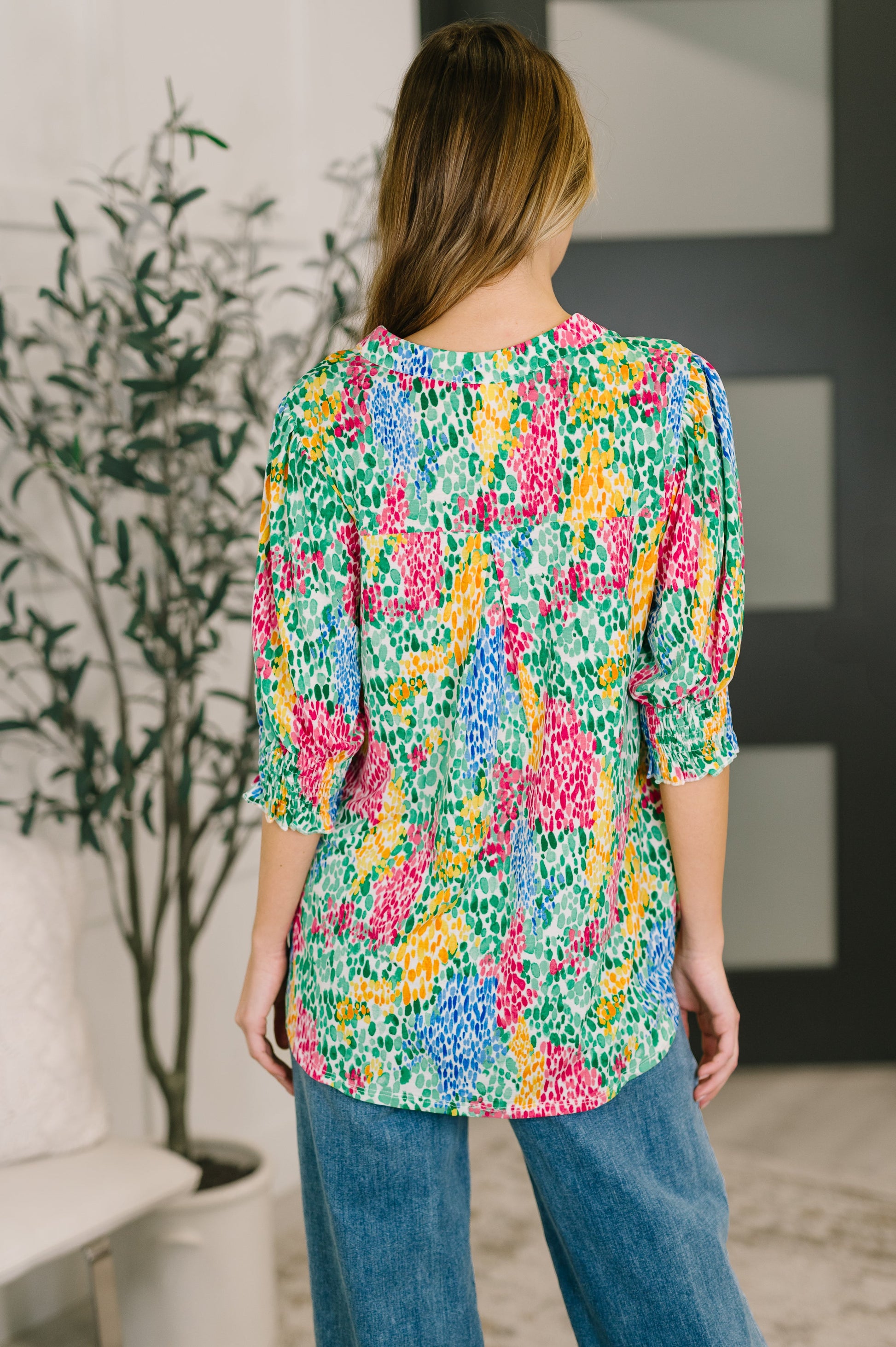 Woman wearing a colorful floral blouse in an indoor setting