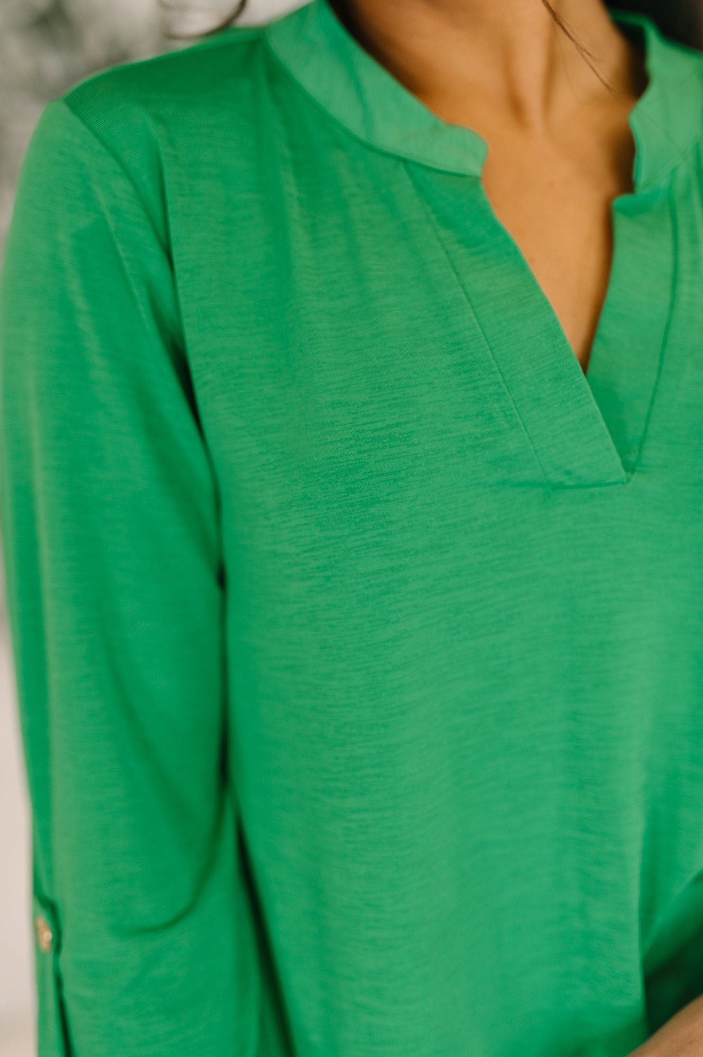 Green blouse with a V-neck and long sleeves on a neutral background
