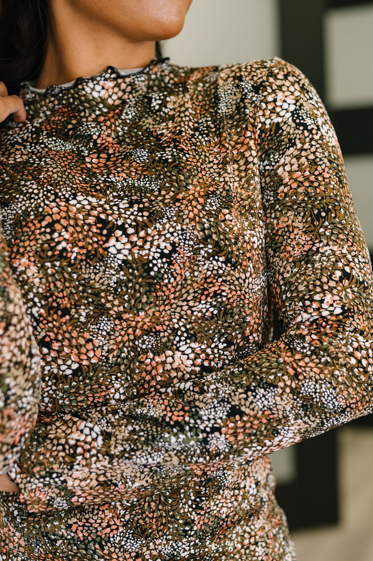 Close-up of a person wearing a patterned long-sleeve top with a blurred background