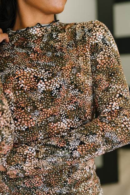Close-up of a person wearing a patterned long-sleeve top with a blurred background