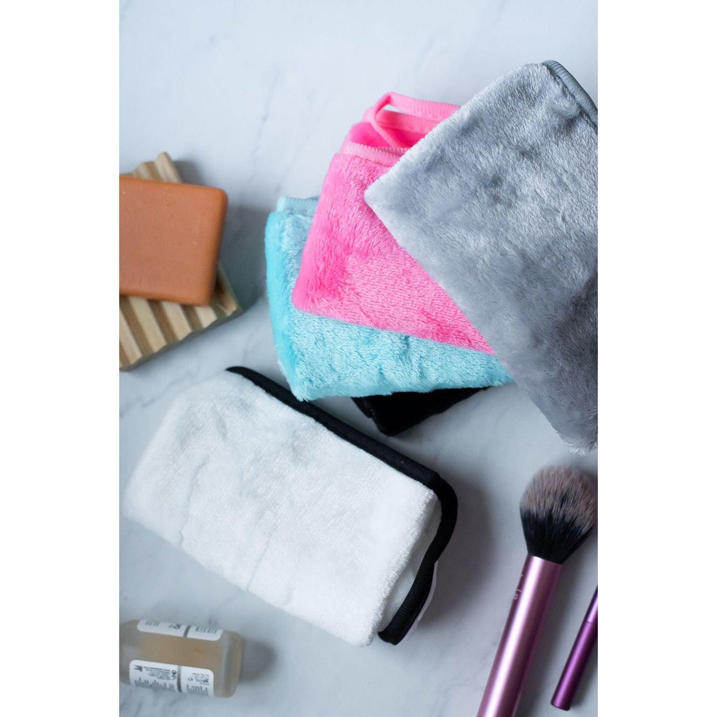 Set of colorful microfiber cloths and makeup brushes on a marble surface