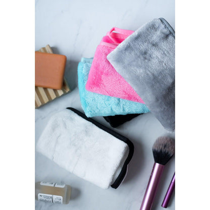 Set of colorful microfiber cloths and makeup brushes on a marble surface