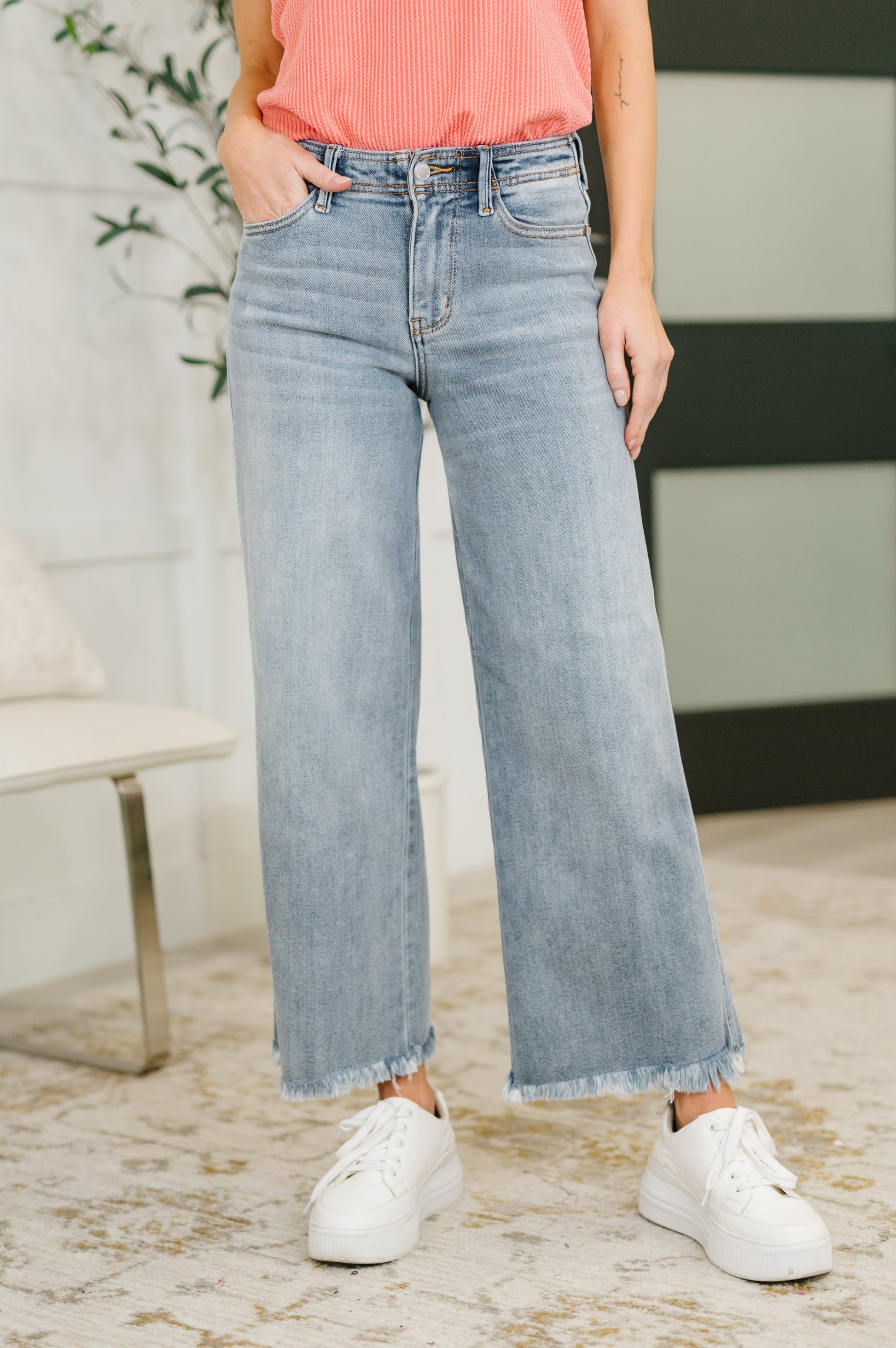 Person wearing light blue jeans and white sneakers indoors.