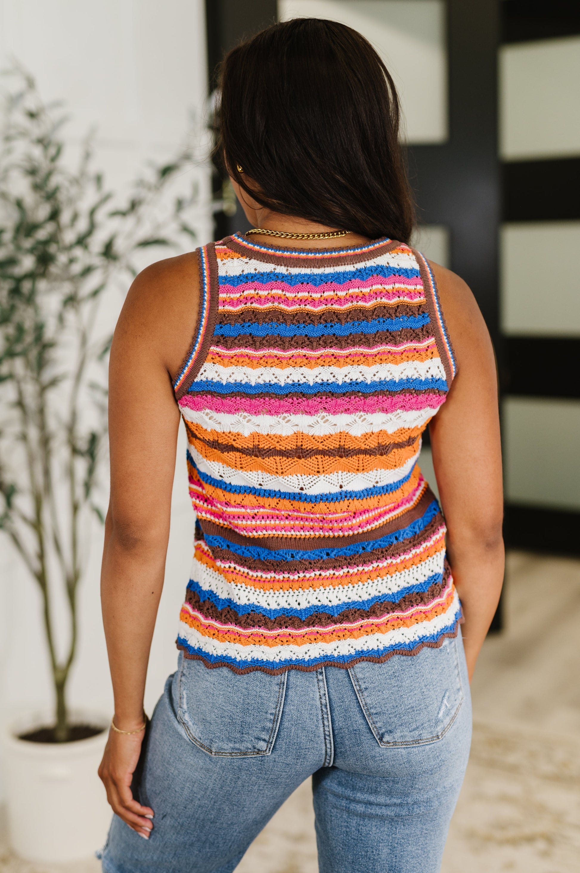 Person wearing a colorful striped tank top and jeans indoors.