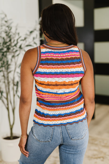 Person wearing a colorful striped tank top and jeans indoors.