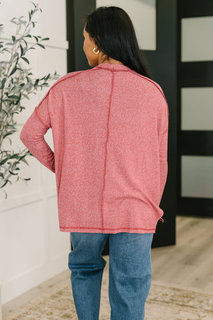 Person wearing a pink jacket and blue jeans standing indoors.