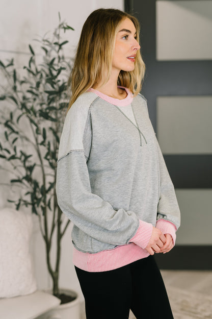 Woman wearing a gray and pink sweater in an indoor setting