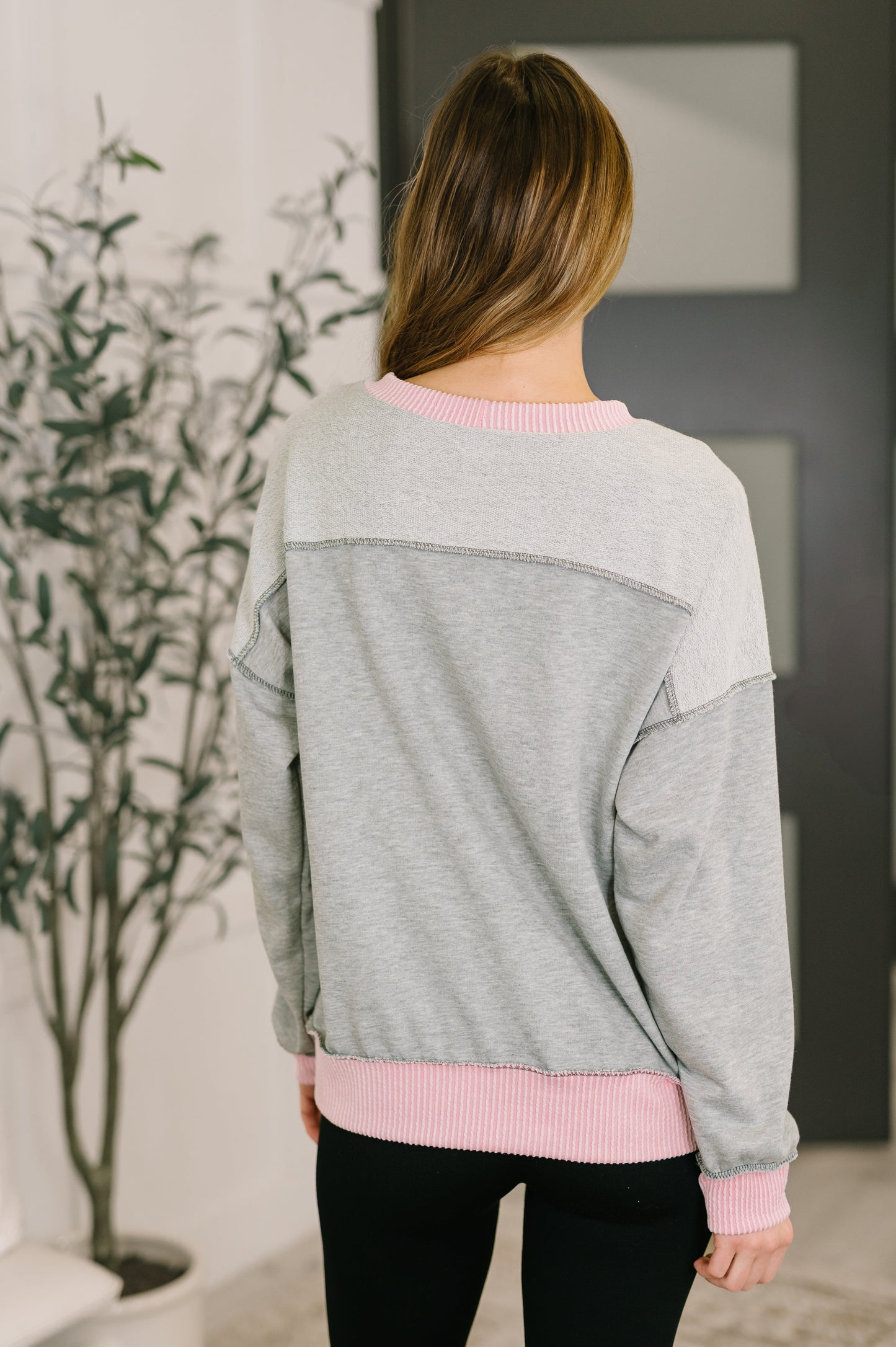 Person wearing a gray and pink sweater in an indoor setting