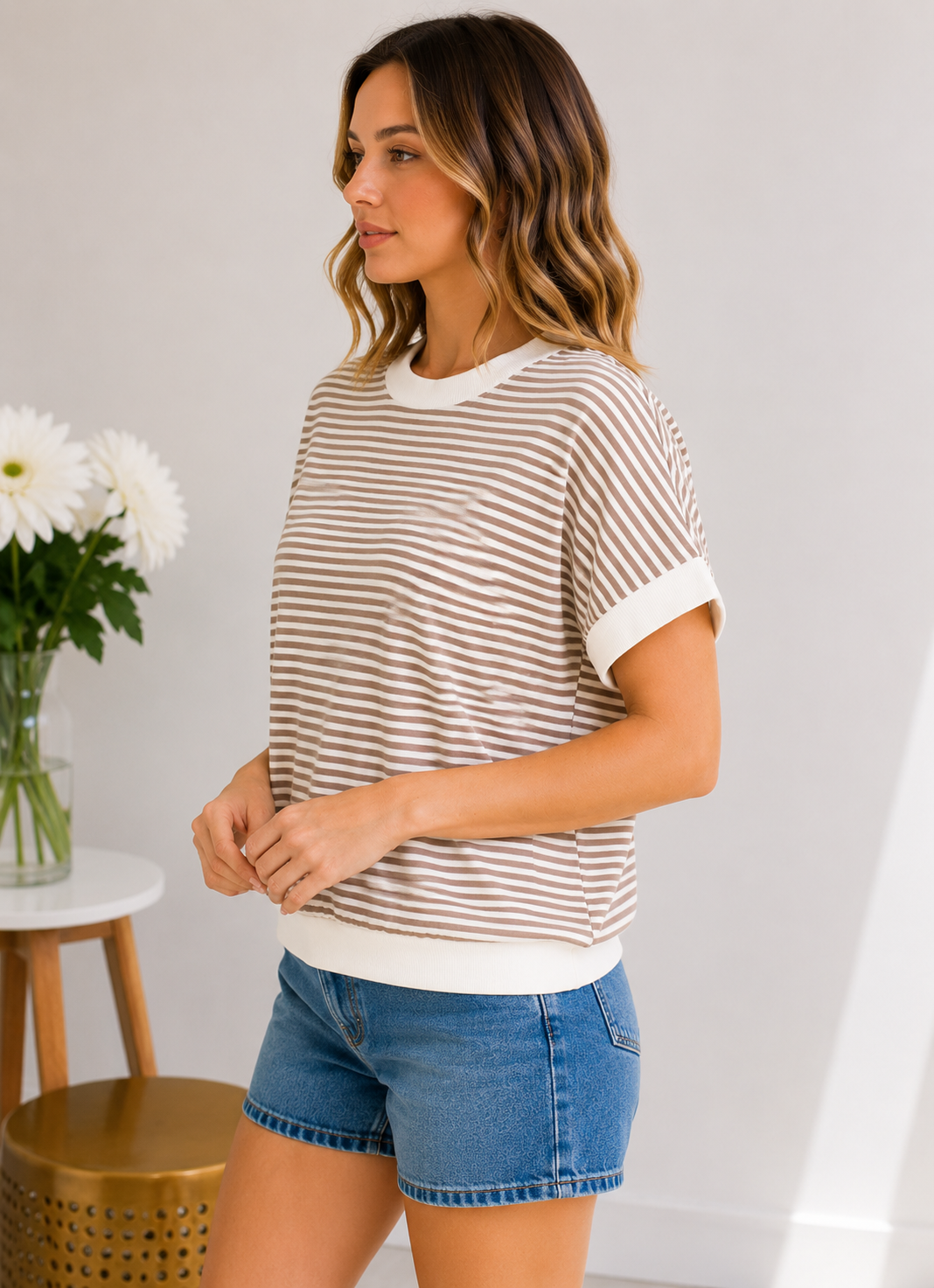 Woman wearing a striped shirt and denim shorts in a casual setting.