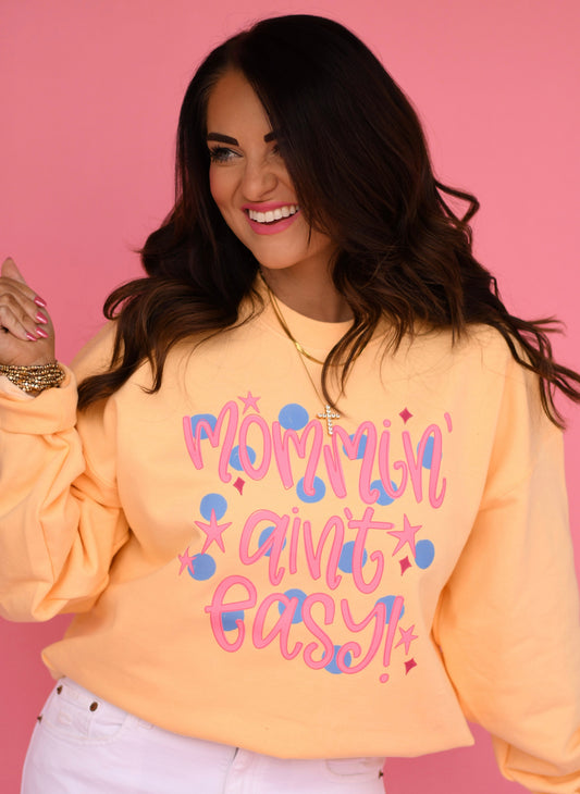 Woman wearing a yellow sweatshirt with colorful text on a pink background