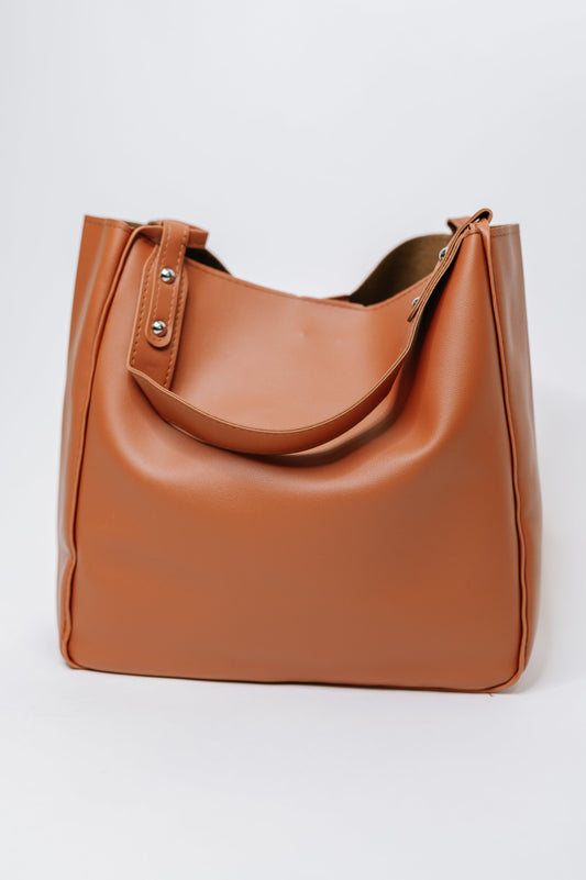 Brown leather shoulder bag on a light gray background