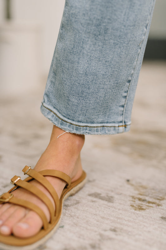 Brown sandal worn with light blue jeans on a blurred background