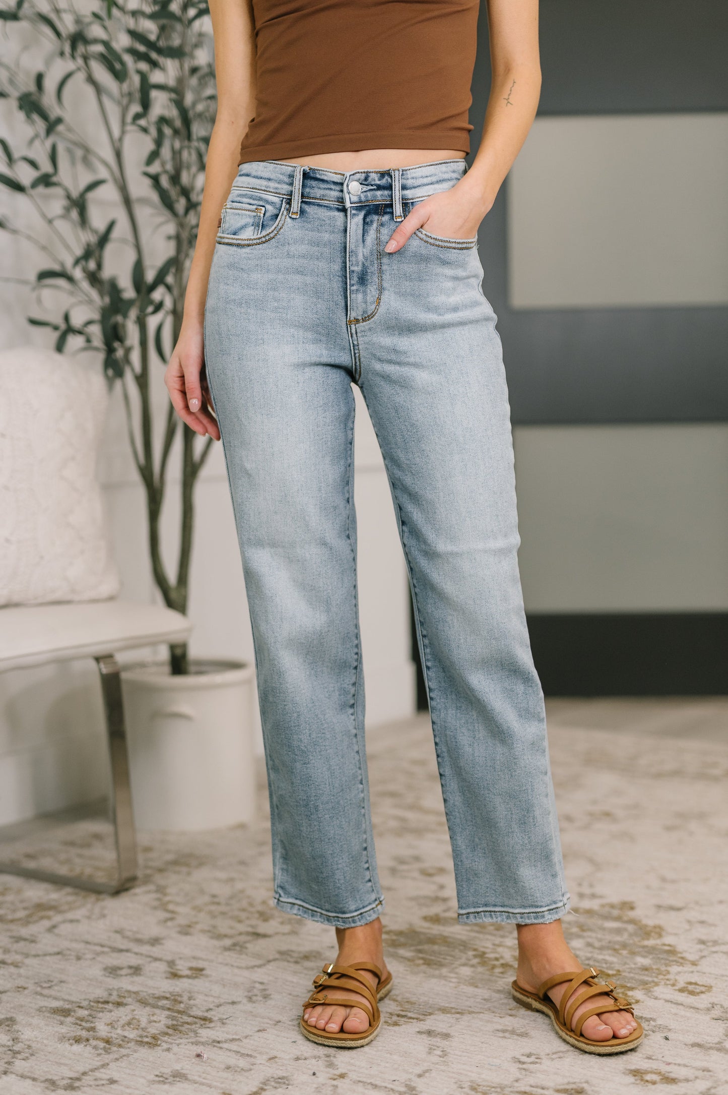 Person wearing light blue jeans and a brown top in an indoor setting.