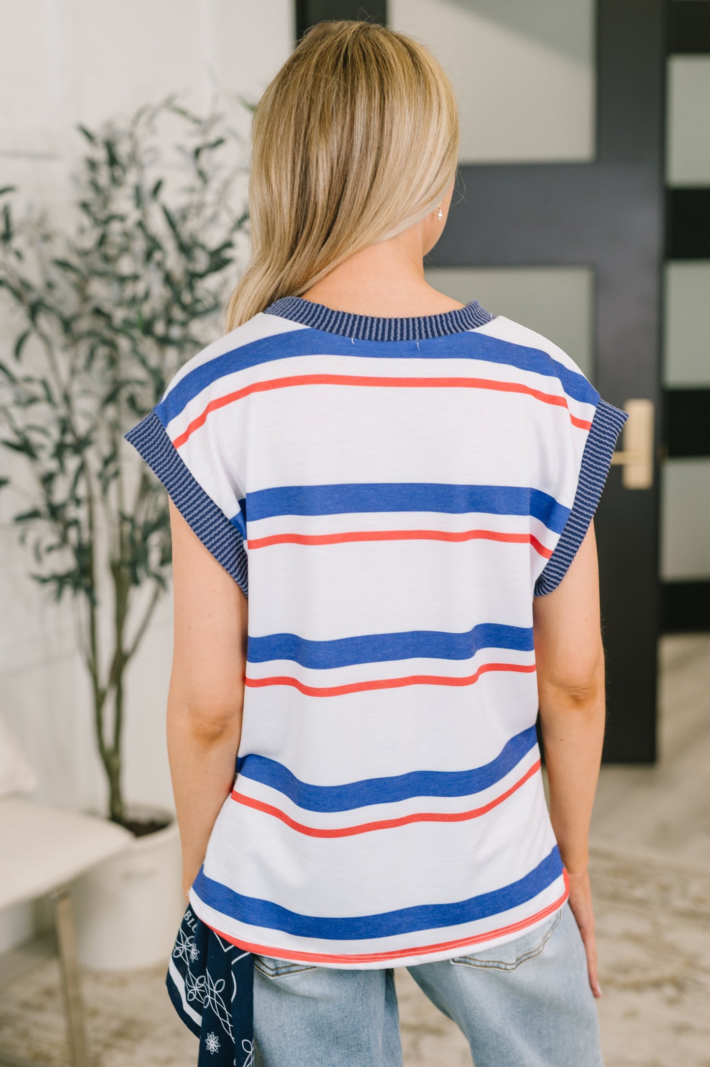 Woman wearing a striped shirt with blue, red, and white colors in an indoor setting.