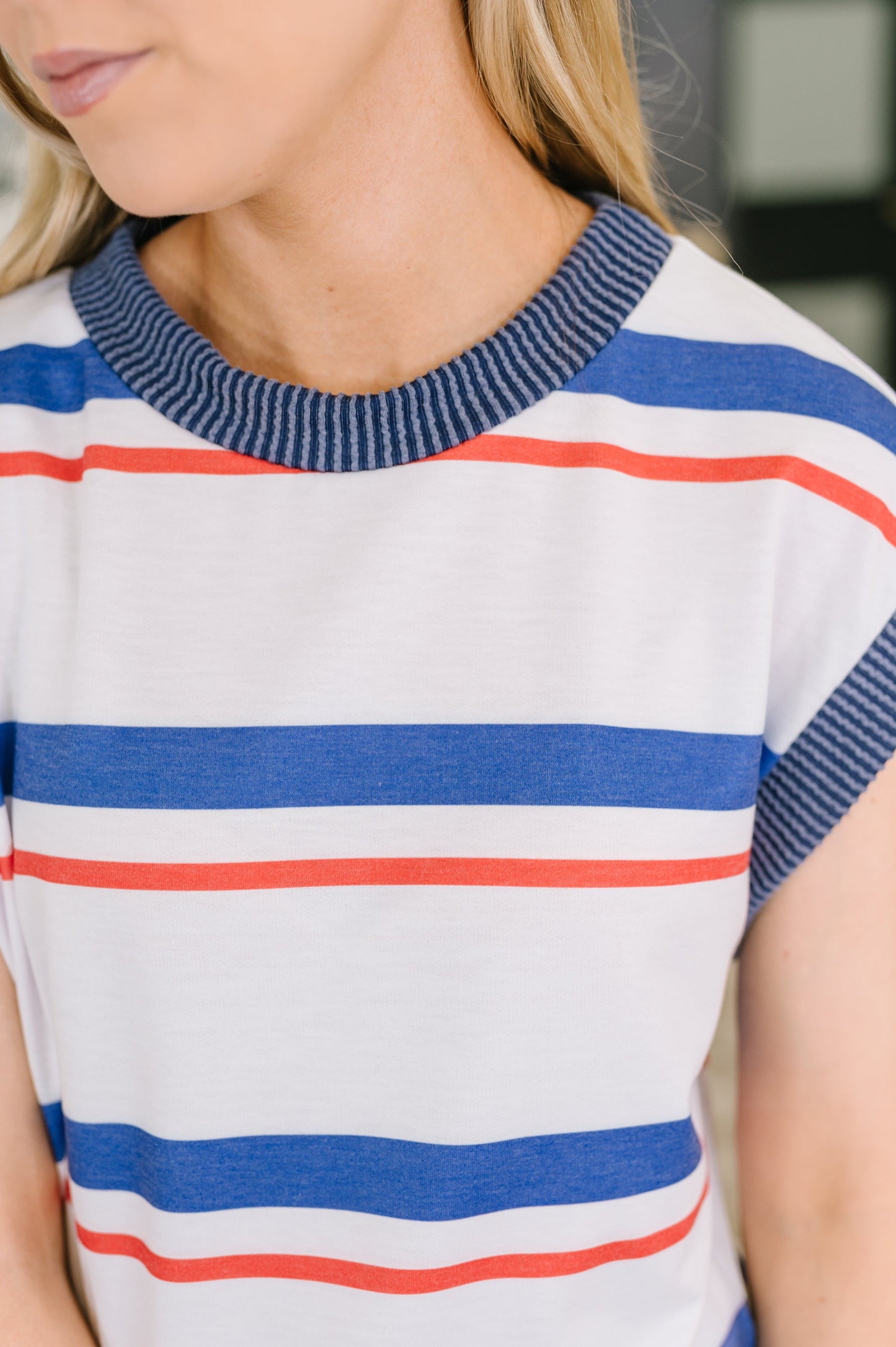 Close-up of a person wearing a striped shirt with blue, red, and white colors.