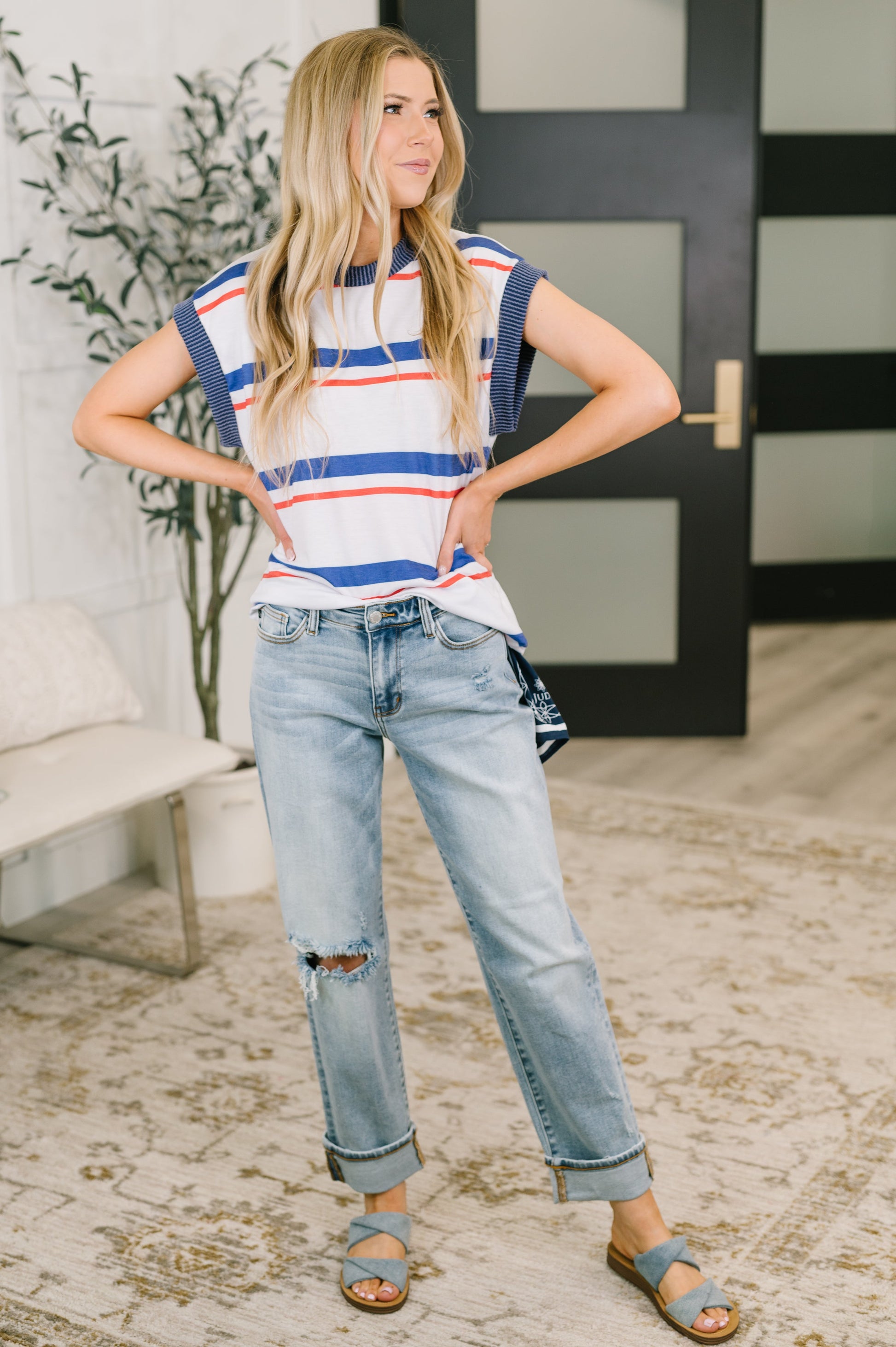Woman wearing a striped shirt and jeans standing indoors.